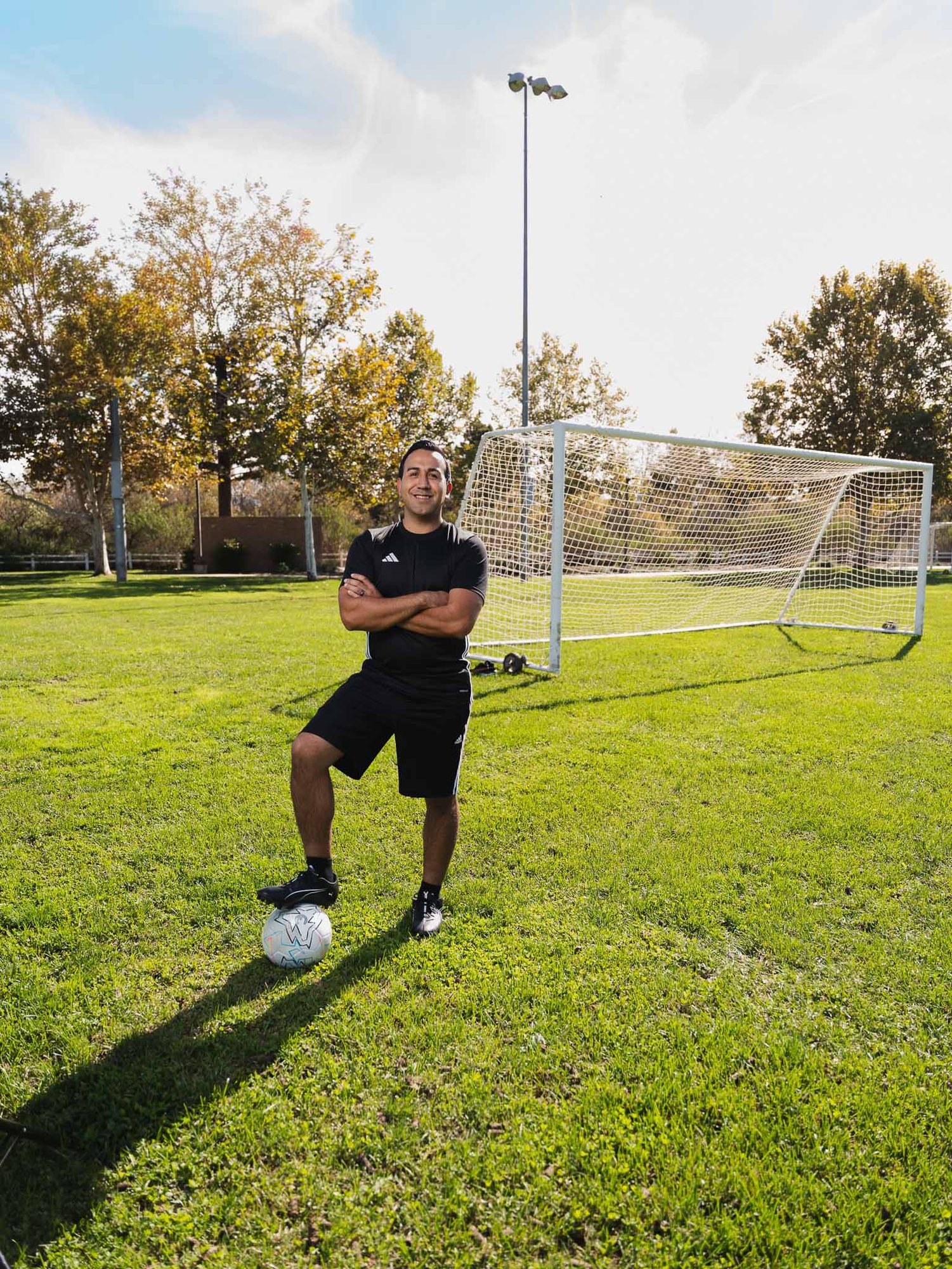 Dr. Anthony Gallegos with a ball on a community soccer field