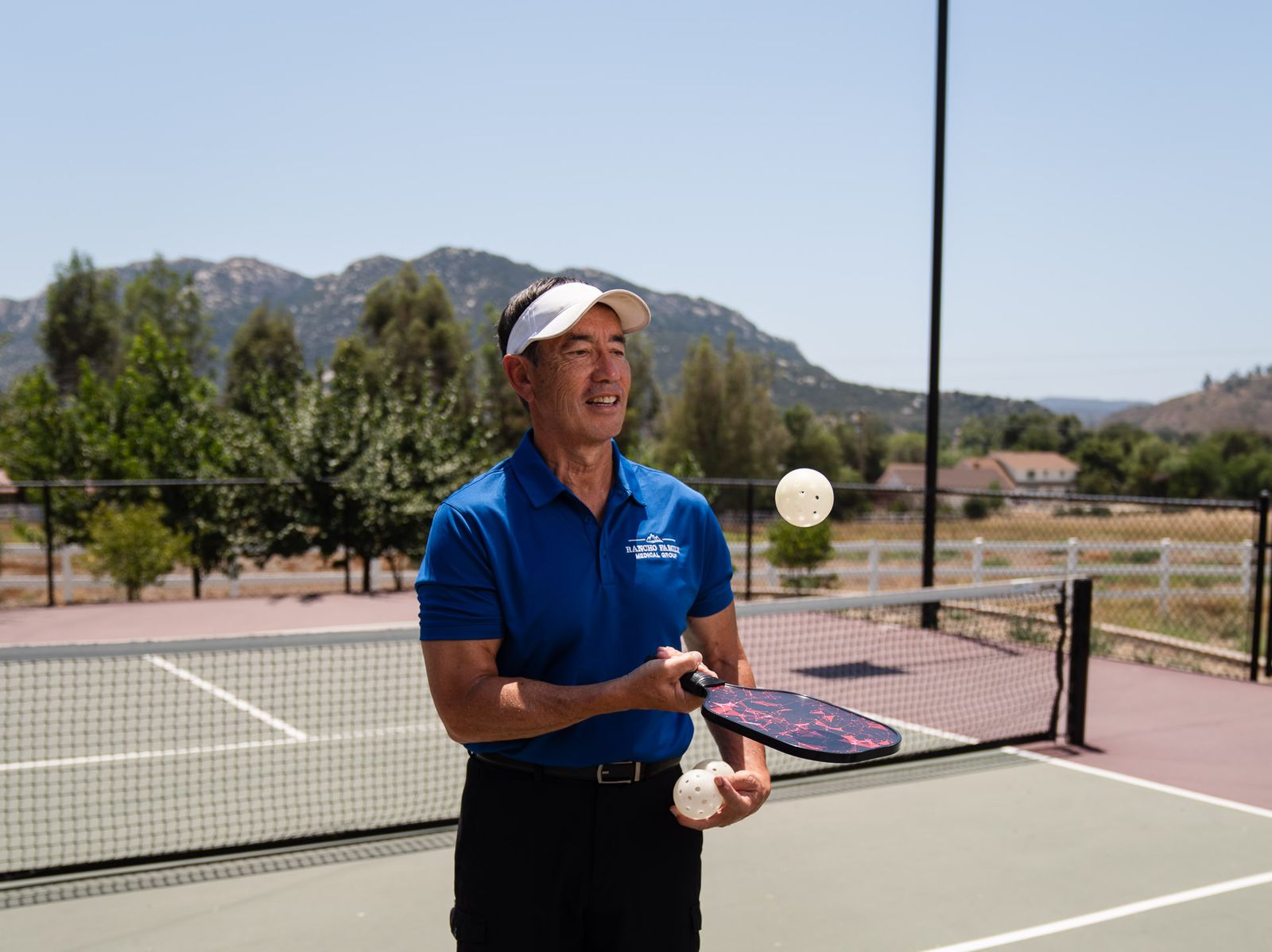 Dr. Jerry Hizon on a pickleball court with the hills behind