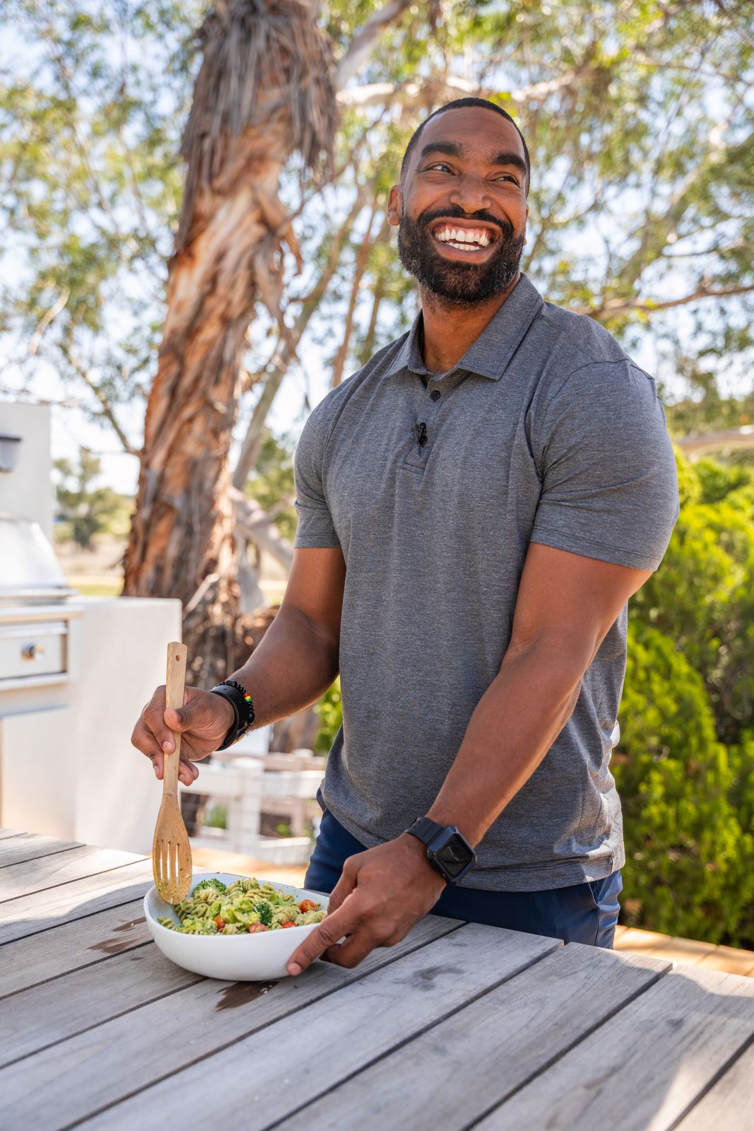 Dr. Kyle Vincent laughing while plating a pesto pasta outdoors